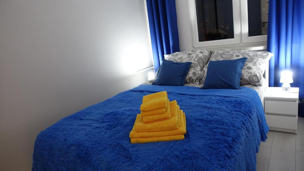Una cama azul con dos toallas amarillas. en Apartament Jakubek, en Polkowice