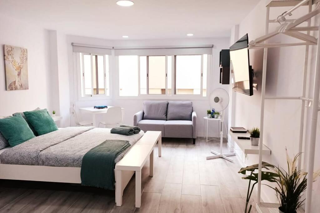 Precioso apartamento a 150 metros de la Playa في لاس بالماس دي غران كاناريا: غرفة نوم بيضاء مع سرير وأريكة