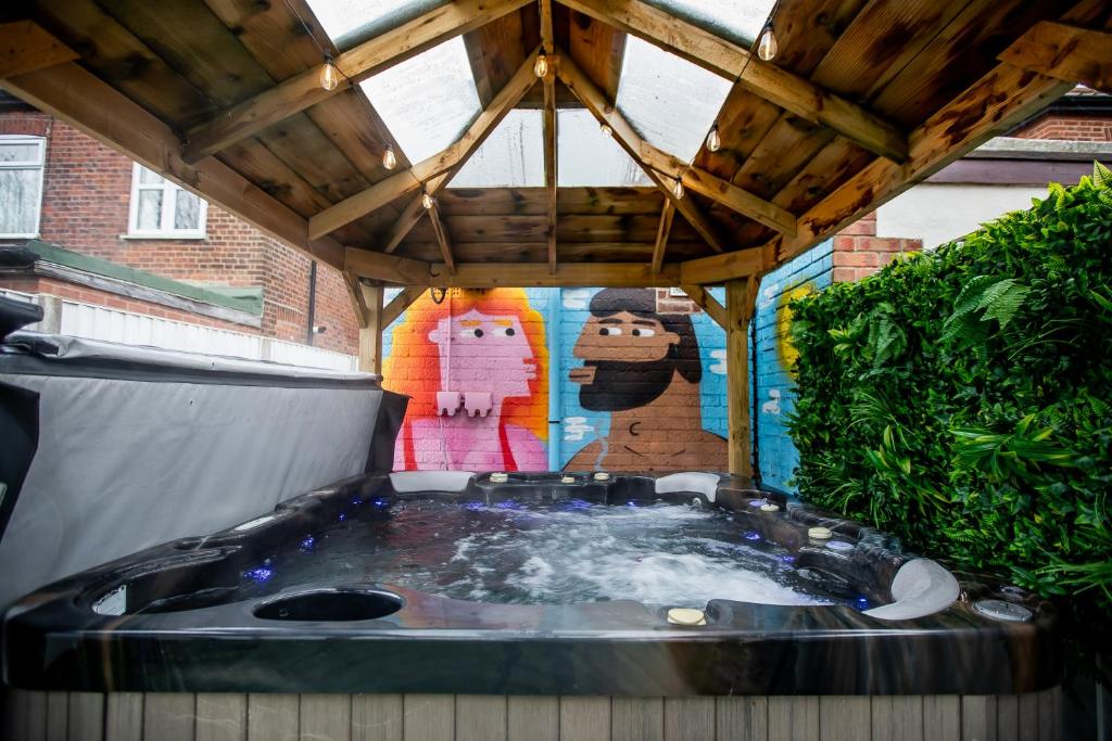 un bain à remous dans une arrière-cour avec un toit en bois dans l'établissement Stunning City Centre House With Hot Tub & Cinema Room, à Norwich