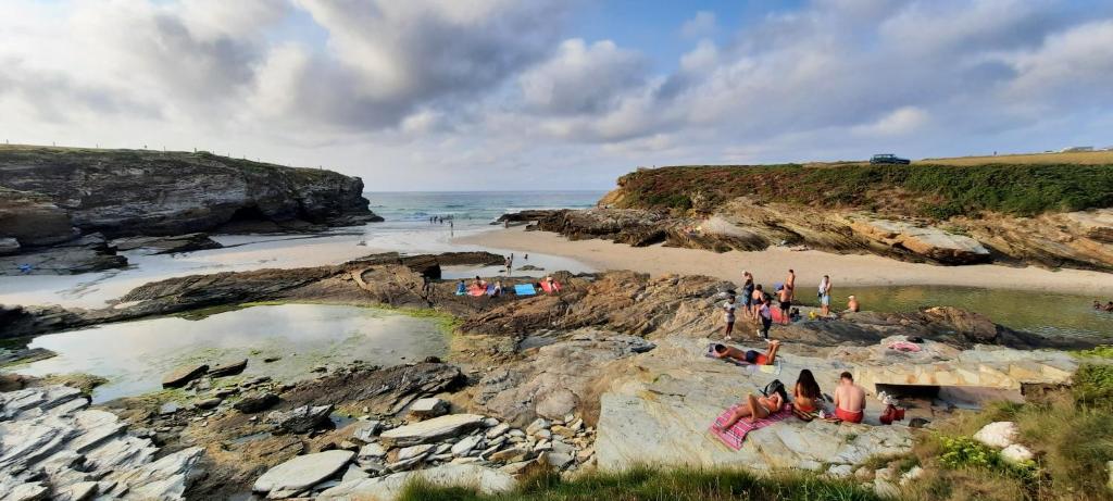a group of people sitting on the rocks on a beach at Apartamentos Turísticos Rosa in Ribadeo