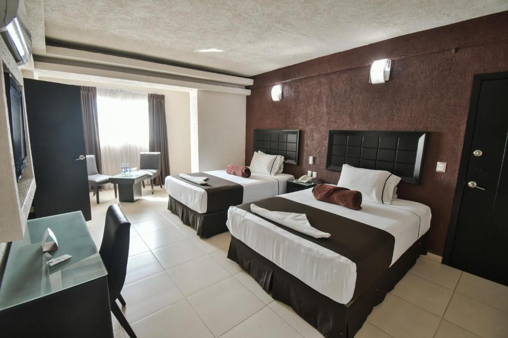 Habitación de hotel con 2 camas y escritorio en Hotel Portonovo Plaza Centro en Guadalajara