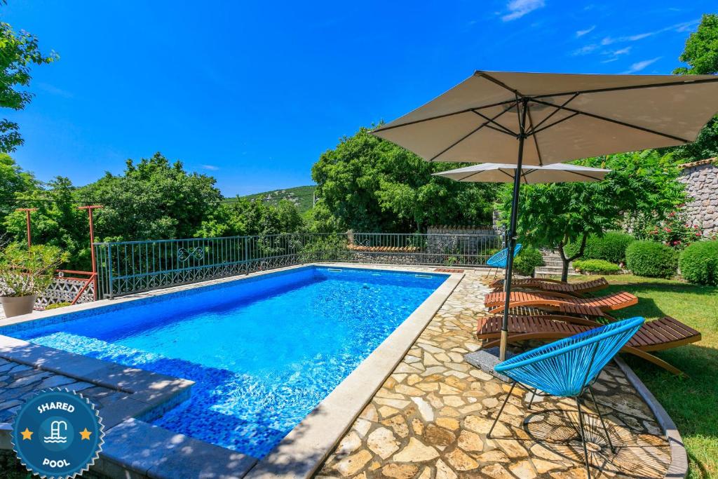 a swimming pool with an umbrella and chairs at Apartment Jurja in Ledenice