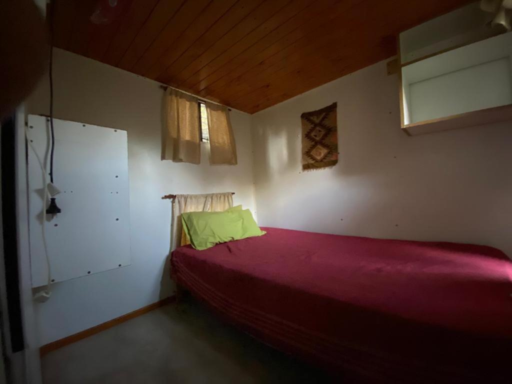1 dormitorio con cama roja y ventana en Casilla Rodante Rural en San Marcos en San Marcos Sierras