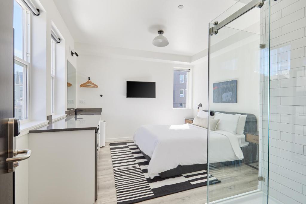 a white bedroom with a bed and a glass walk in shower at Sonder The Boylston in Seattle