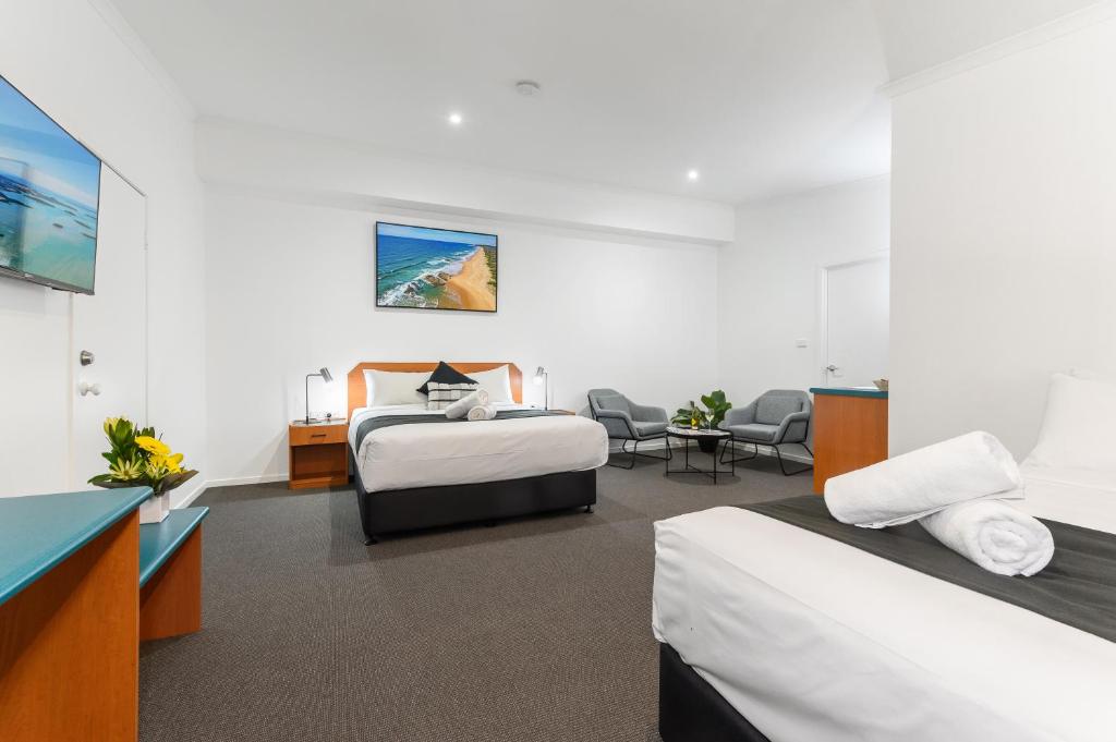 a hotel room with two beds and a desk at CQ Motel Gladstone in Gladstone