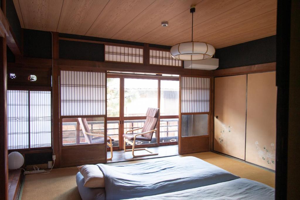 a bedroom with a bed and a window with a chair at Hostel Ayame in Kyoto