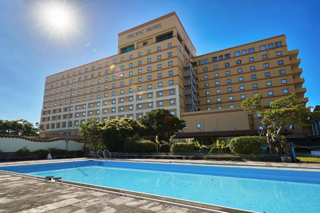 a hotel with a swimming pool in front of a building at Pacific Hotel Okinawa in Naha