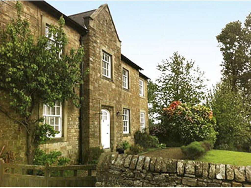 una gran casa de ladrillo con una pared de piedra delante de ella en Low Gingerfield Farm B&B, en Richmond