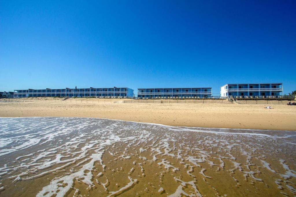 einen Strand mit einem Gebäude im Hintergrund und dem Meer in der Unterkunft Montauk Blue Hotel in Montauk