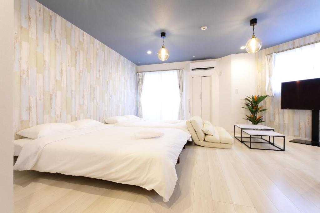 a bedroom with two beds and a flat screen tv at AQA ART 江の島 in Fujisawa