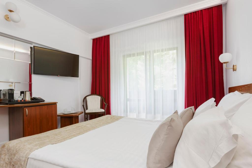 a bedroom with a large bed with red curtains at Manor Ski Hotel in Predeal