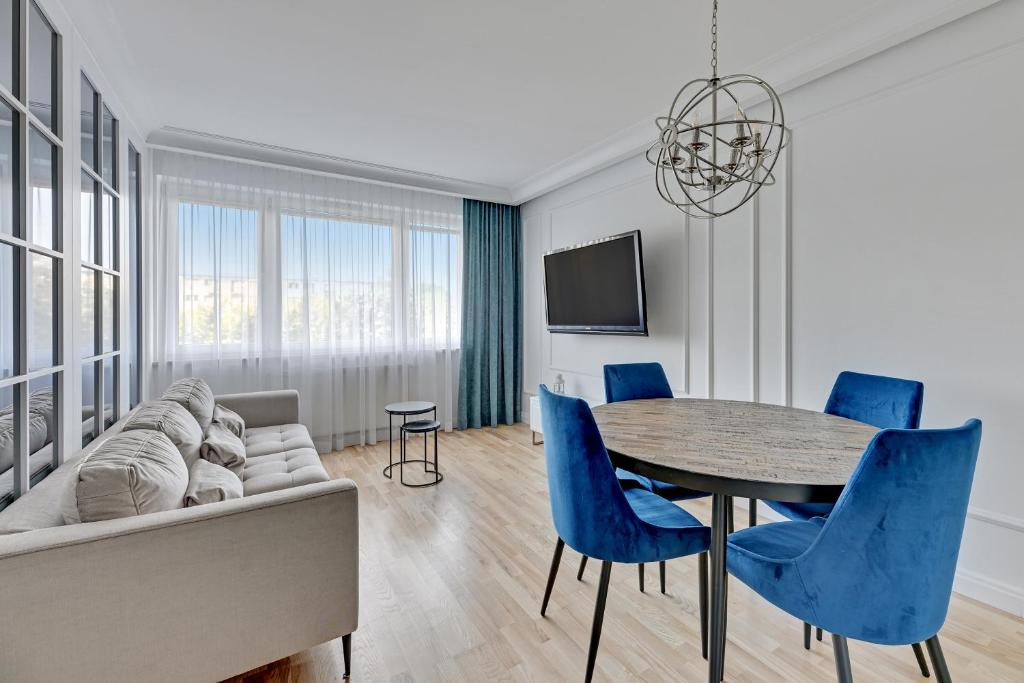 a living room with a couch and a table and blue chairs at Downtown Apartments Seaside Primore in Gdańsk