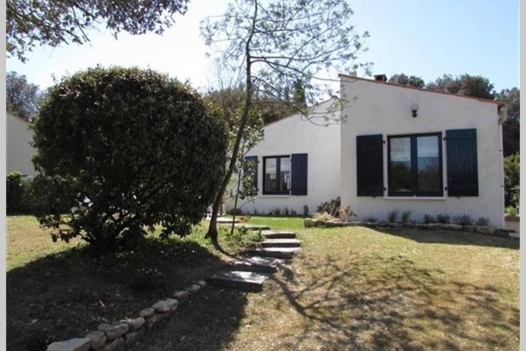 a white house with black windows and a tree at Maison Vert d'Eau in Grand-Village-Plage