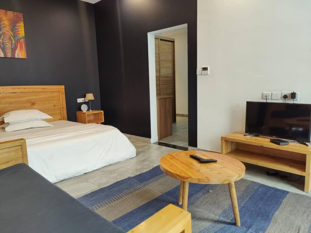 1 dormitorio con cama, mesa y TV en Tanzanite Apartment（Tanzanite Park） en Dar es Salaam