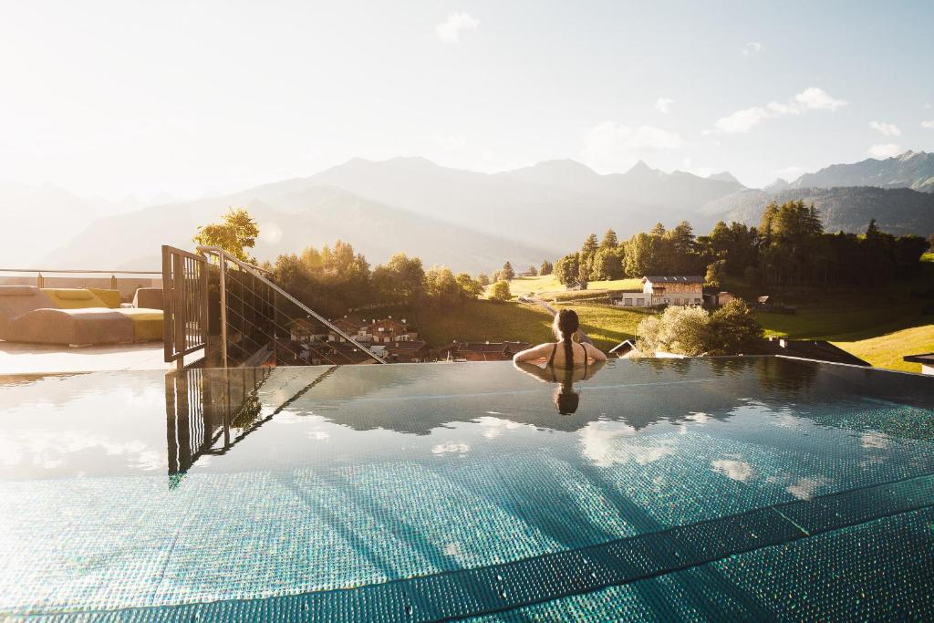a person in a swimming pool with mountains in the background at Alpine Resort Goies Superior in Ladis