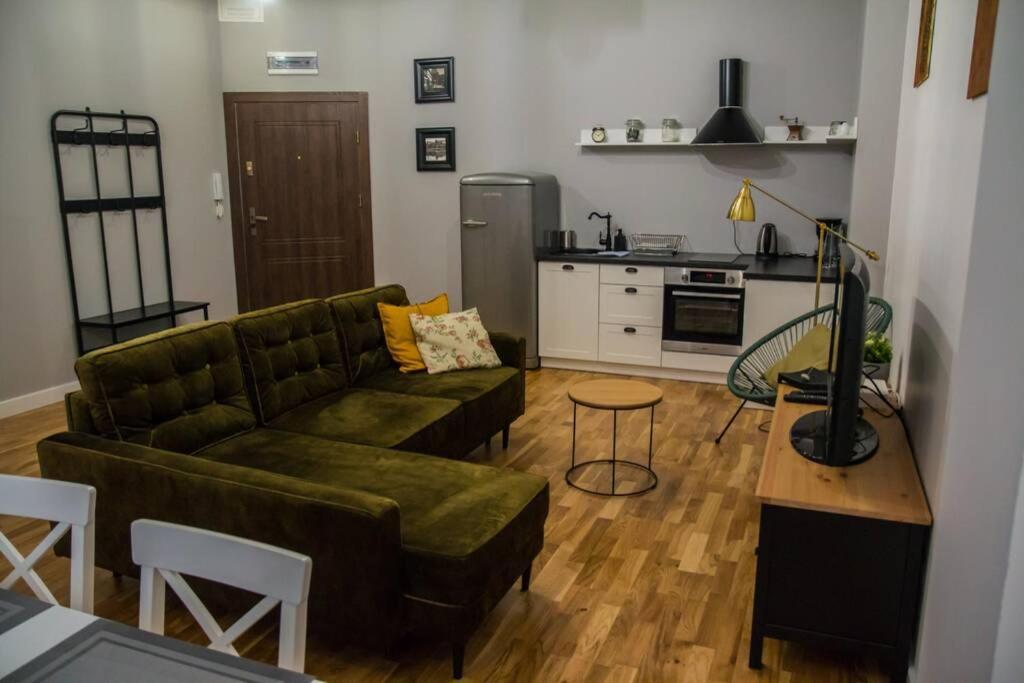 a living room with a green couch and a kitchen at Salonik u Kazimierza in Toruń