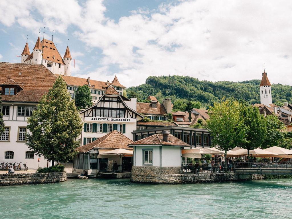 eine Gruppe von Gebäuden am Fluss in einer Stadt in der Unterkunft Hotel Krone Thun in Thun