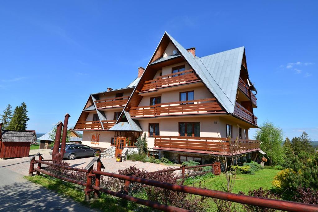 uma grande casa de madeira com um telhado de gambrel em Miś Pokoje Gościnne em Bukowina Tatrzańska