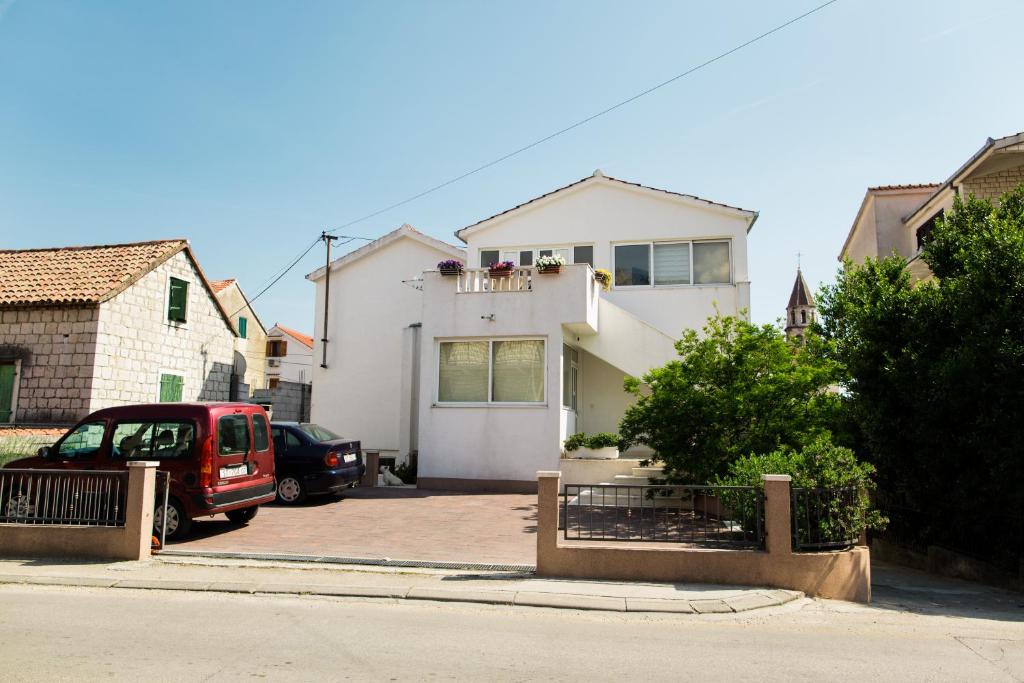 una casa blanca con un coche aparcado en una entrada en Apartments Kanajet, en Kaštela