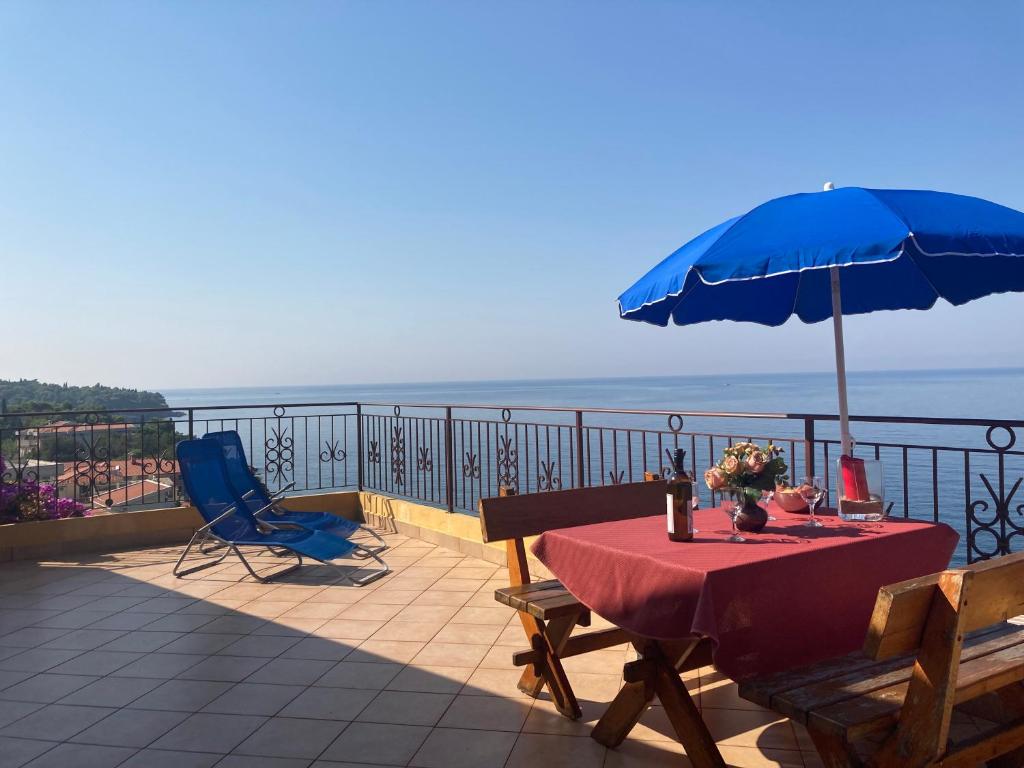 a table with a blue umbrella and chairs on a balcony at Monterama Apartments in Sutomore