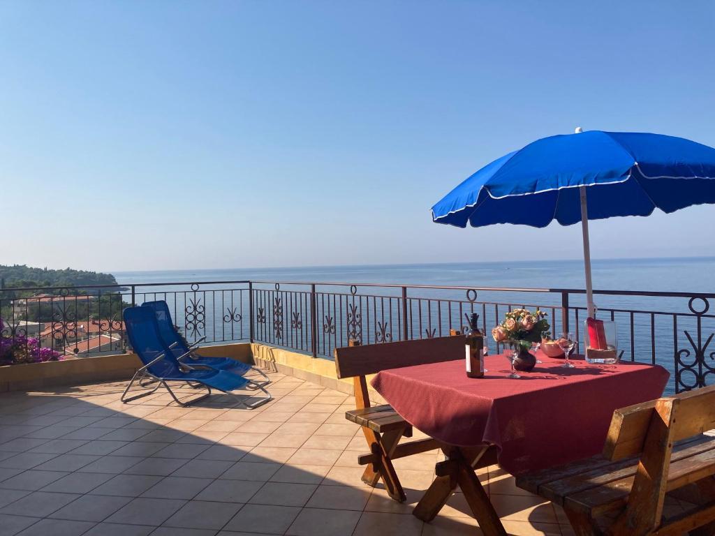 einen Tisch mit einem blauen Sonnenschirm und Stühlen auf dem Balkon in der Unterkunft Monterama Apartments in Sutomore