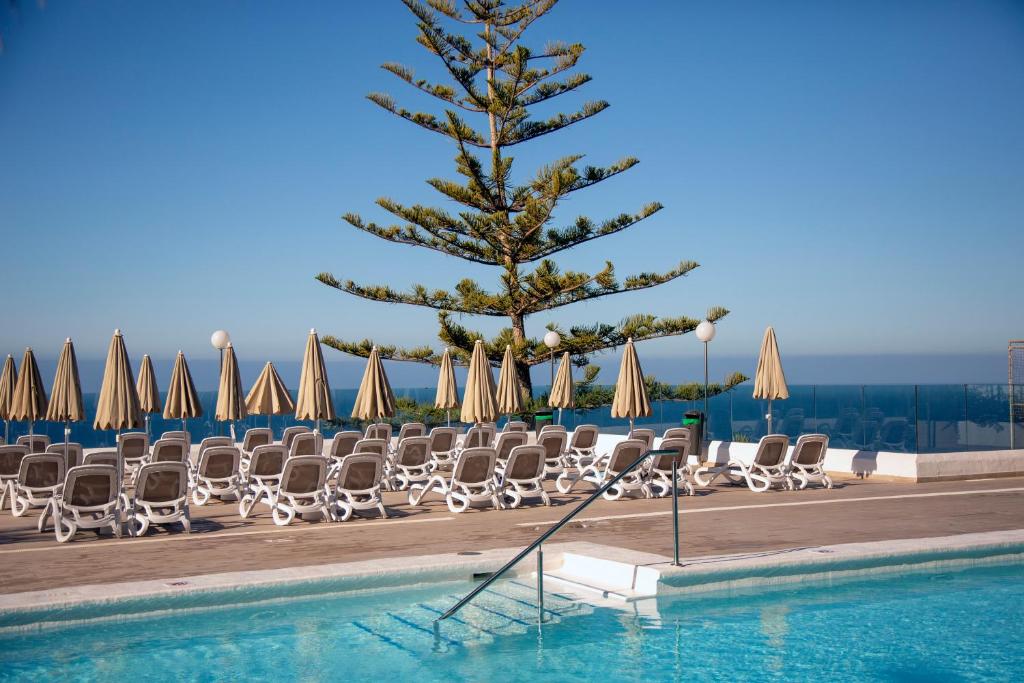 a christmas tree and lounge chairs next to a swimming pool at Hotel Altamar in Puerto Rico de Gran Canaria