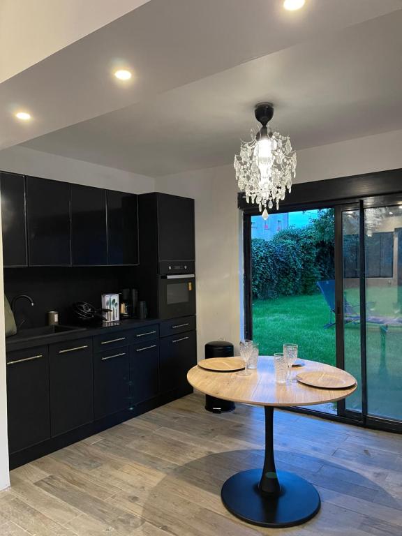 a kitchen with a table and a chandelier at La grange de Livia in Ferrière-la-Grande