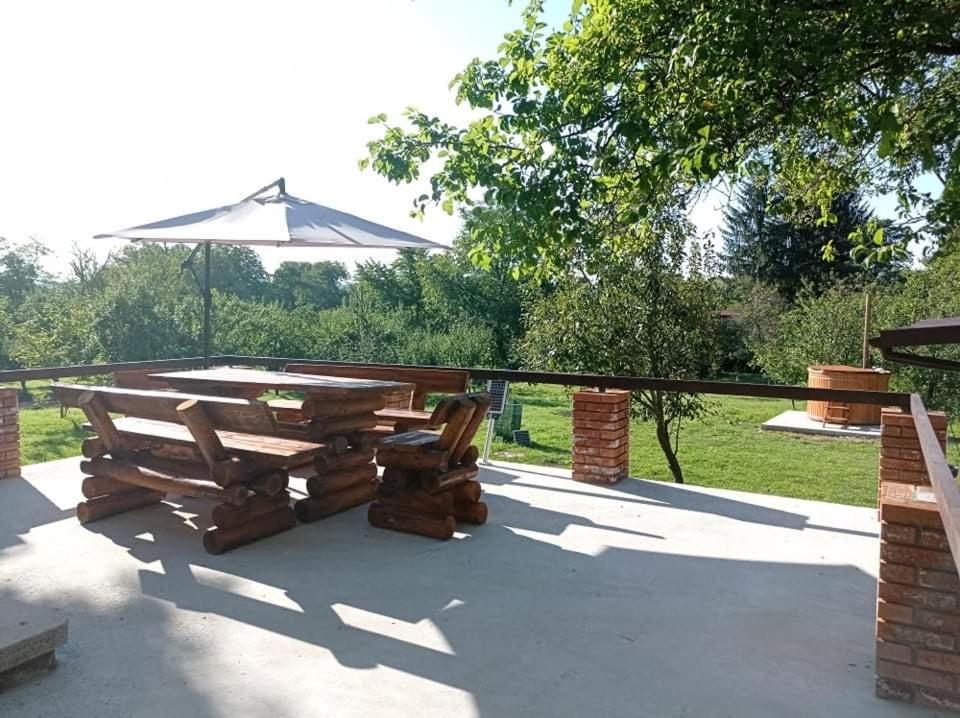 un patio con mesa de picnic y sombrilla en Casa rurala cu padurice si livada en Campina