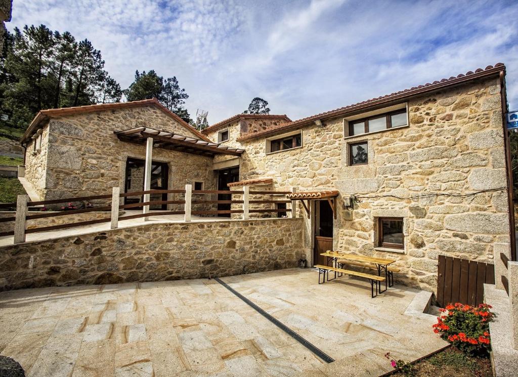 a stone house with a porch and a bench at Casa Crego in Dumbría