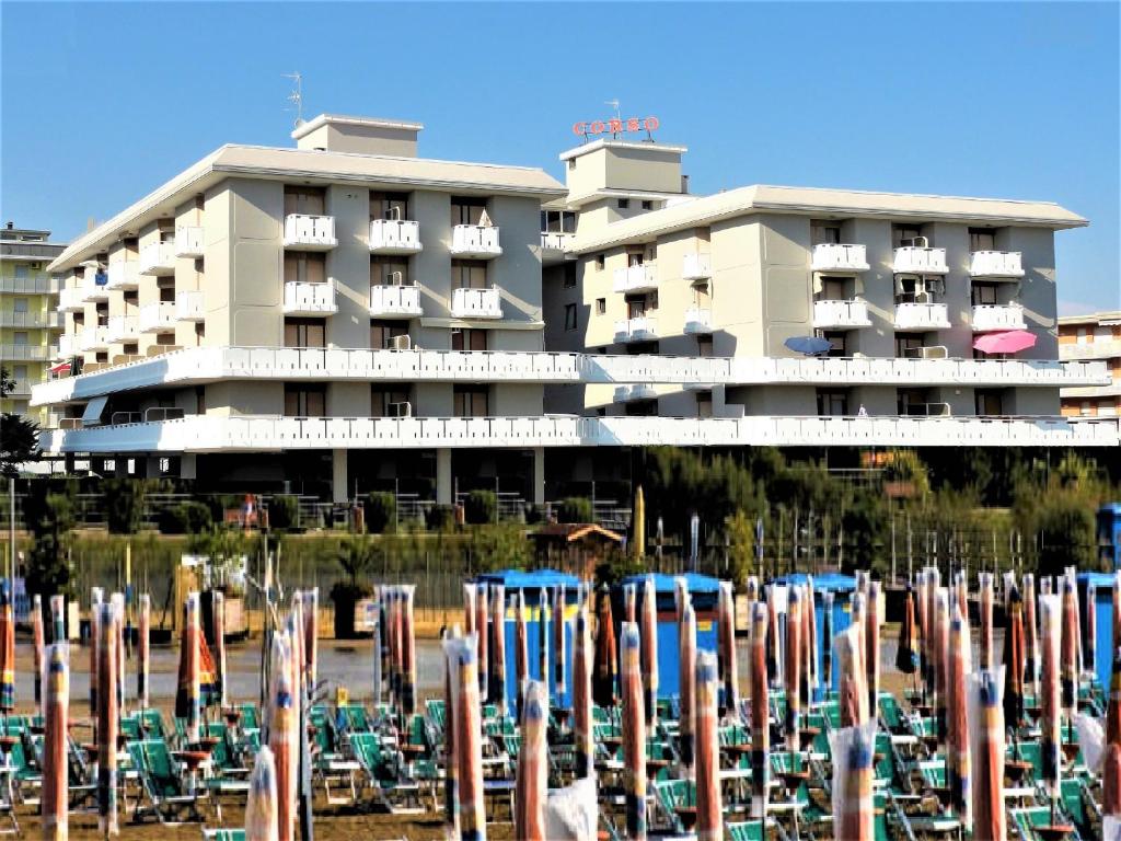 un hotel con un montón de sombrillas de playa delante de él en Corso - Appartamenti, en Bibione