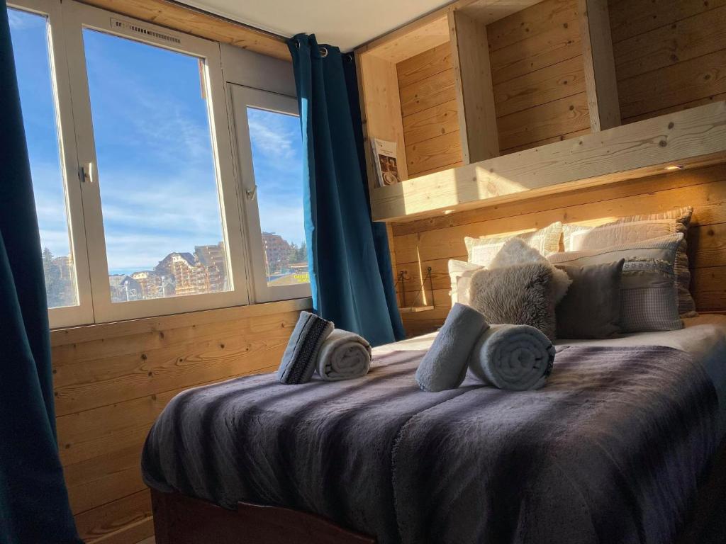 - une chambre avec un lit doté de rideaux bleus et de fenêtres dans l'établissement Résidence Les Portes du Soleil - Propriétés Mont Amour, à Avoriaz