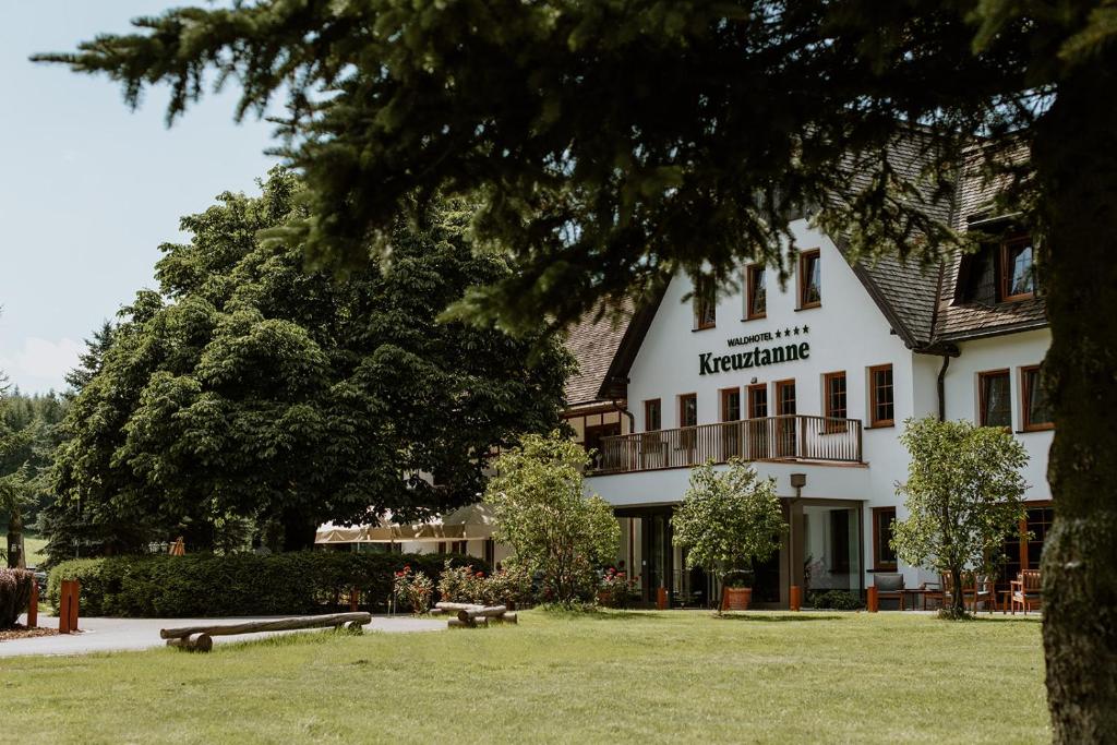 a large white building with a tree in front of it at Waldhotel Kreuztanne in Sayda