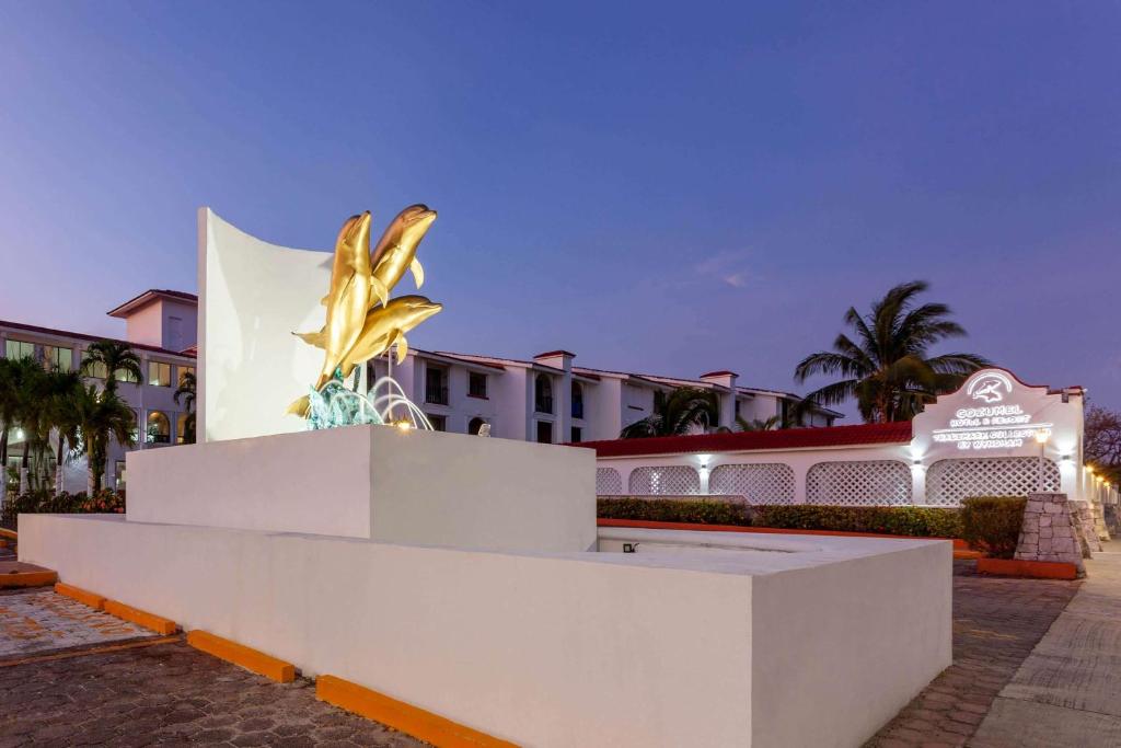 een gouden standbeeld voor een gebouw bij Cozumel Hotel & Resort Trademark Collection by Wyndham in Cozumel