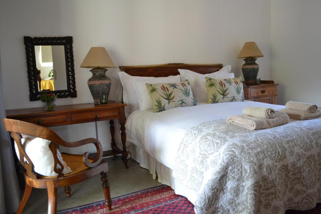a bedroom with a bed with a mirror and a chair at Kuruma Farm Cottages in Worcester