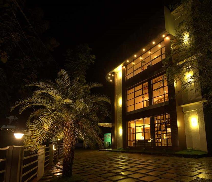 a palm tree in front of a building at night at HOTEL LA SERENE Mattannur in Mattanūr