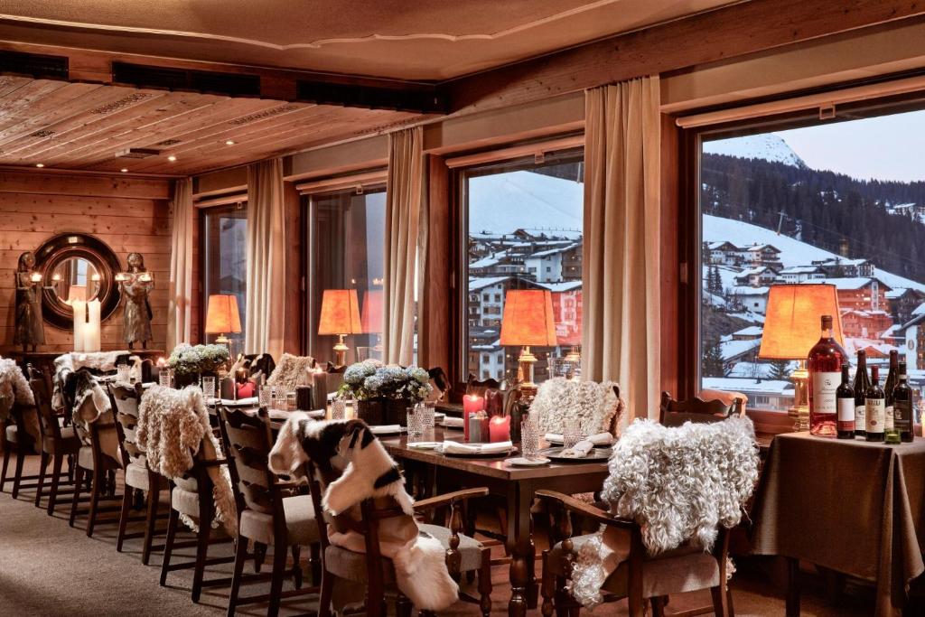 a dining room with a table and chairs and windows at Kristiania Lech in Lech am Arlberg