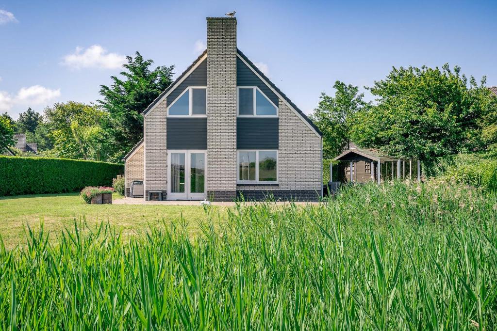 uma casa num campo com relva alta em Villapark Kamperfoelie 71 em De Koog