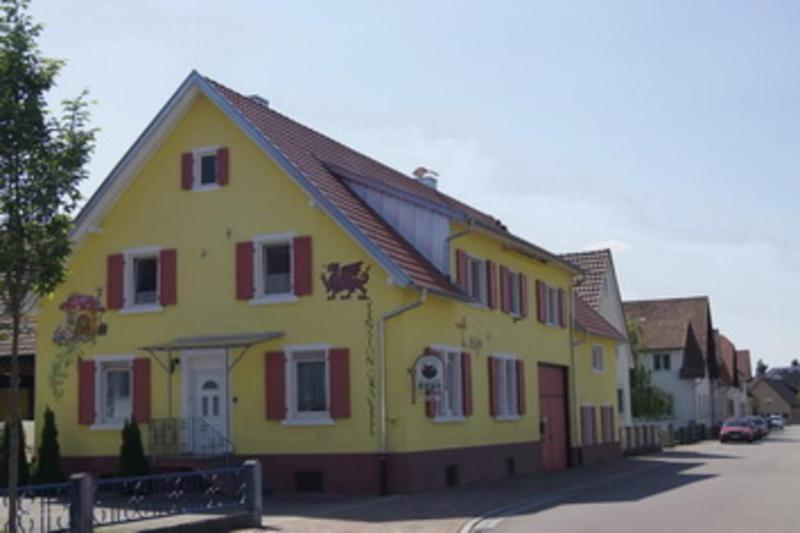 una casa amarilla con persianas rojas en una calle en Gaestehaus Gravell en Rust