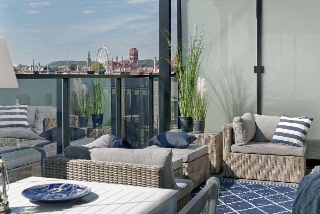 a balcony with wicker furniture and a view of the city at Nadmotławie Sauna & Gym by Blue Mandarin in Gdańsk