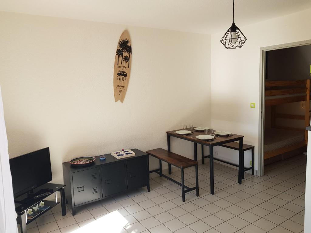 een woonkamer met een tafel en een surfplank aan de muur bij Studio à moins de 50m de l'école de voile... in La Turballe