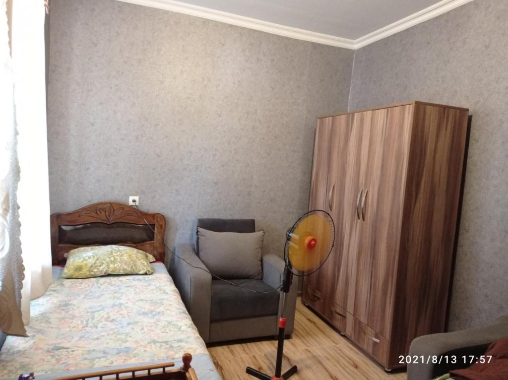 een slaapkamer met een bed, een stoel en een kast bij Green House in Kachretʼi