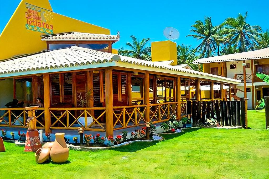 a large wooden building with a grass yard at Hotel e Pousada Tetiaroa in Barra Grande