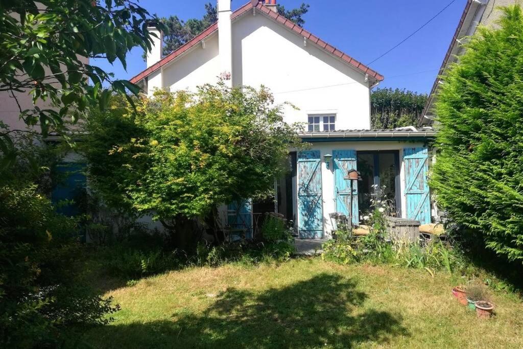 a white house with blue doors and a yard at Maison avec jardin à 30 minutes de Paris in Brunoy