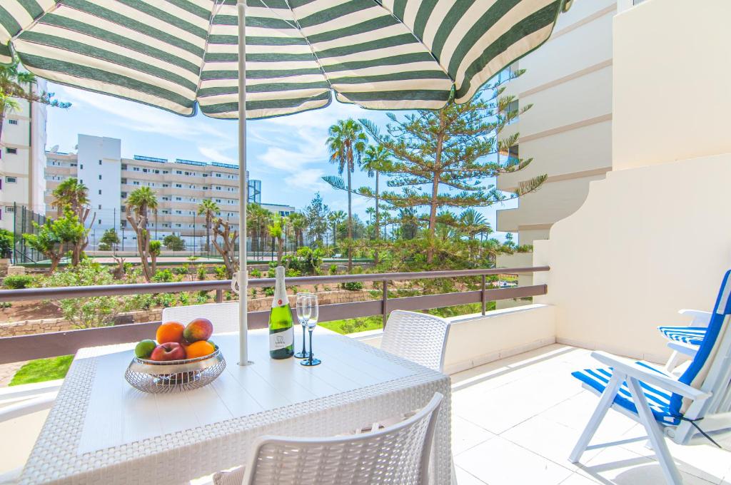 un tavolo e delle sedie su un balcone con un ombrellone di El Dorado Garden View PH04 ad Arona