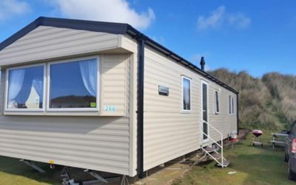 a white trailer with a window on a field at Cosy 3-Bed Caravan combe haven st Leonards on sea in Hollington