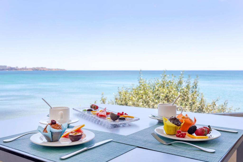 a table with two plates of food on the beach at Melia Alicante in Alicante