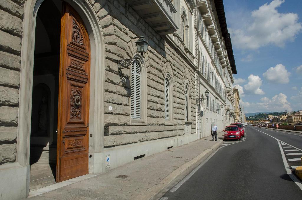 un coche rojo estacionado en una calle al lado de un edificio en Lungarno Vespucci Charming Apartment, en Florencia