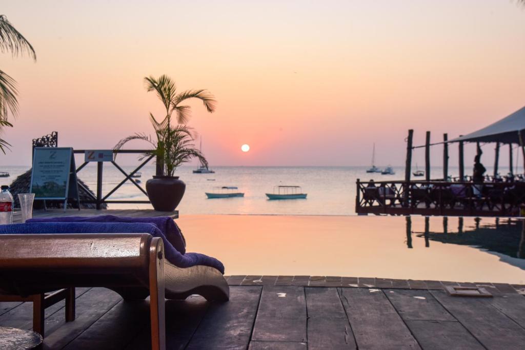 a sunset over the ocean with boats in the water at Z Hotel in Nungwi