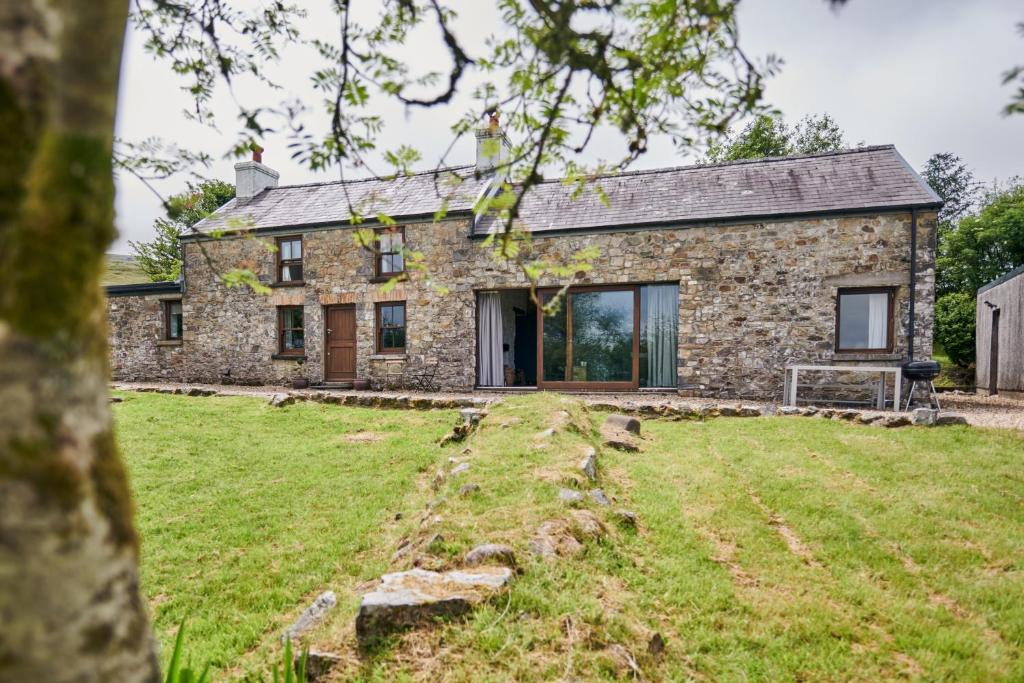 an exterior view of a stone house with a yard at Wildhaven- Idylic rural farmhouse with log burner and countryside views in Gwynfe