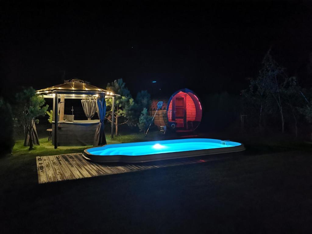 uma piscina iluminada à noite com uma tenda em Dom na Mazurach WrzoSPA em Stare Juchy